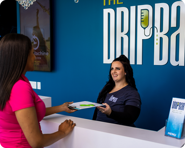 A woman handing a clipboard with a pen to a patient