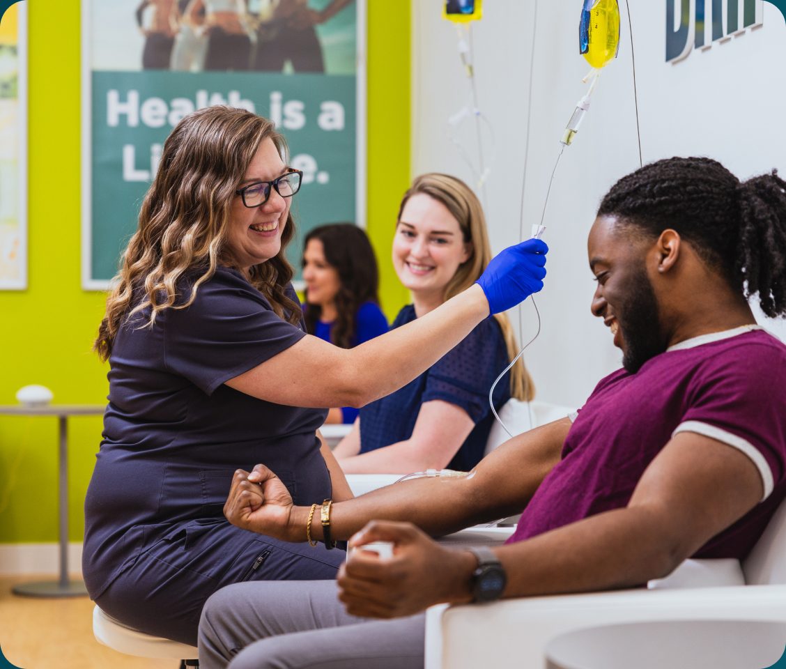 A DRIPBaR nurse starting an IV drip for a smiling client
