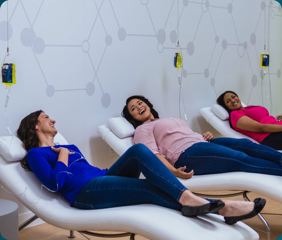 Three friends relaxing in recliners during a group IV therapy session